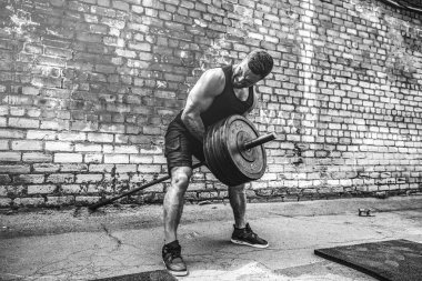 Atletik bir adam bir halter ile çalışma dışarı. Güç ve motivasyon. Arka kasları için egzersiz