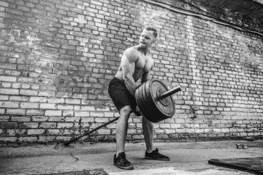 Atletik bir adam bir halter ile çalışma dışarı. Güç ve motivasyon. Arka kasları için egzersiz