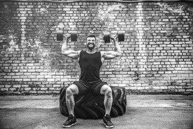 kaslı adam bir tuğla duvara dumbbell ile yapıyor