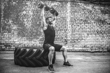 kaslı adam bir tuğla duvara dumbbell ile yapıyor
