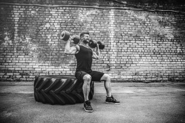 kaslı adam bir tuğla duvara dumbbell ile yapıyor