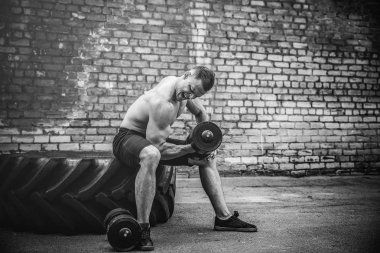 kaslı adam bir tuğla duvara dumbbell ile yapıyor