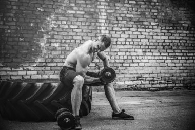 kaslı adam bir tuğla duvara dumbbell ile yapıyor