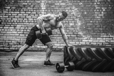Atletik bir adam bir halterle çalışma dışarı. Güç ve motivasyon. Arka kasları için egzersiz