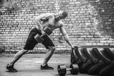 Atletik bir adam bir halterle çalışma dışarı. Güç ve motivasyon. Arka kasları için egzersiz