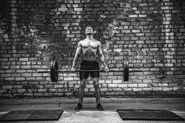 Gespierde fitness man doen deadlift een barbell boven zijn hoofd in outdoor, straat sportschool. Functionele training. — Stockfoto