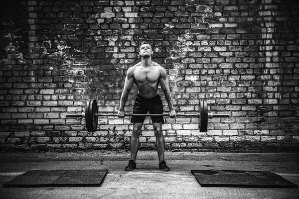 Un uomo muscoloso che fa ginnastica all'aperto con un bilanciere in testa. Formazione funzionale . — Foto Stock