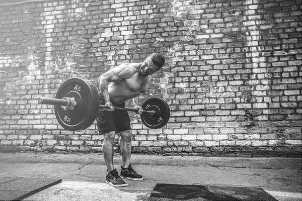 Hombre atlético haciendo ejercicio con una barra. Fuerza y motivación. Ejercicio para los músculos de la espalda — Foto de Stock