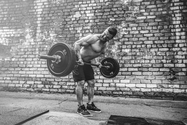 Hombre atlético haciendo ejercicio con una barra. Fuerza y motivación. Ejercicio para los músculos de la espalda —  Fotos de Stock