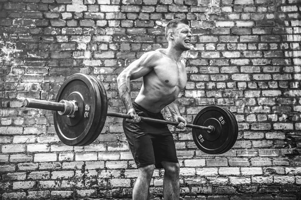 Hombre atlético haciendo ejercicio con una barra. Fuerza y motivación. Ejercicio para los músculos de la espalda —  Fotos de Stock