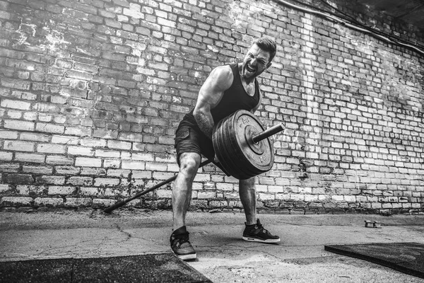 Hombre atlético haciendo ejercicio con una barra. Fuerza y motivación. Ejercicio para los músculos de la espalda — Foto de Stock