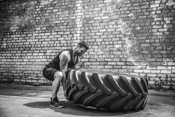 Izmos fitness félmeztelen férfi mozgó nagy gumiabroncs. — Stock Fotó