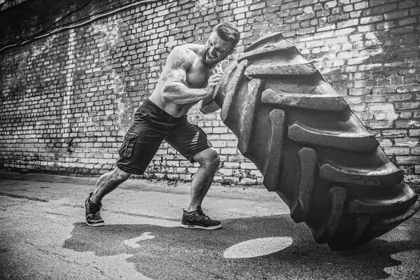 Muskulöse Fitness hemdloser Mann bewegt großen Reifen. — Stockfoto