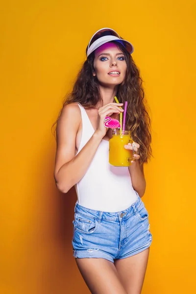 Sexy Woman in white swimsuit and blue jeans shorts, trendy visor holding beverage — Stock Photo, Image