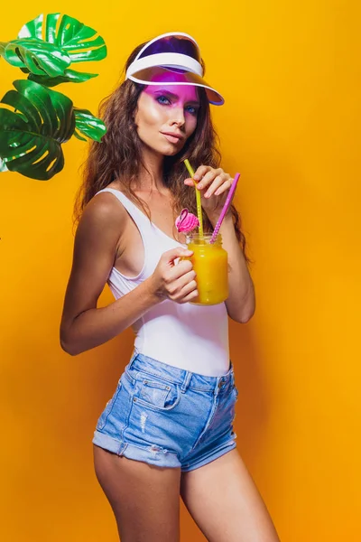 Sexy Woman in white swimsuit and blue jeans shorts, trendy visor holding beverage — Stock Photo, Image