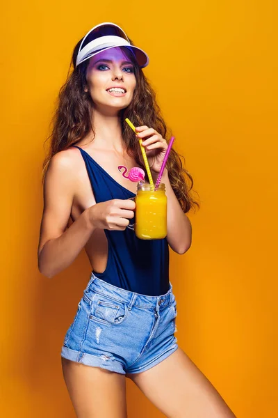 Sexy Frau im weißen Badeanzug und blauen Jeans-Shorts, trendiges Visier mit Getränken — Stockfoto