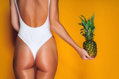 Kadın kalça, seksi eşek. Bir ananas elinde tutan genç sportif kadın.