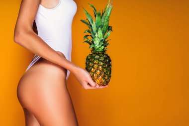 Kadın kalça, seksi eşek. Bir ananas elinde tutan genç sportif kadın.