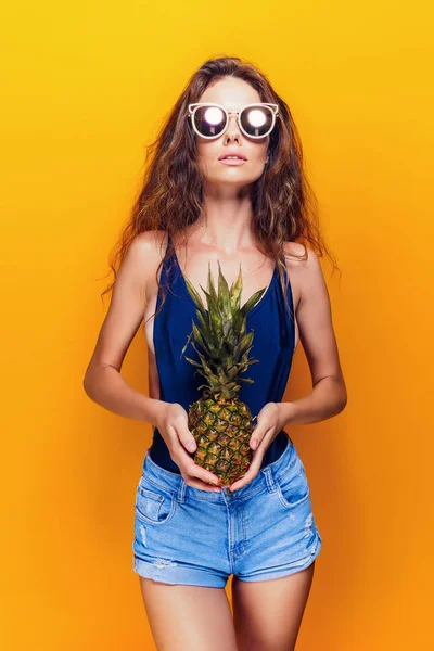 Mujer en traje de baño aislado sobre fondo amarillo sosteniendo piña . — Foto de Stock