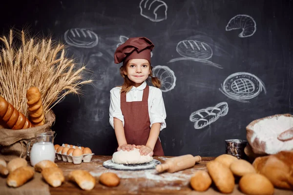 Menina amassando massa de farinha à mesa — Fotografia de Stock