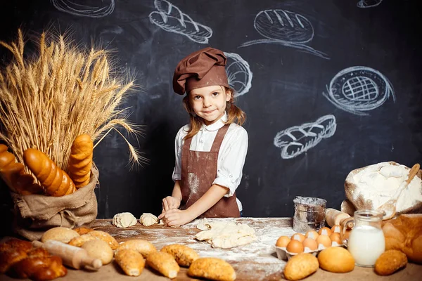 Menina amassando massa de farinha à mesa — Fotografia de Stock