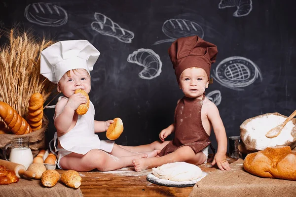 Charming little toddlers in aprons on table with bread Stock Picture