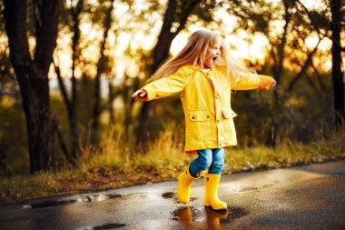 mutlu çocuk kız sarı ceket anmd kauçuk su birikintisine atlama botlar