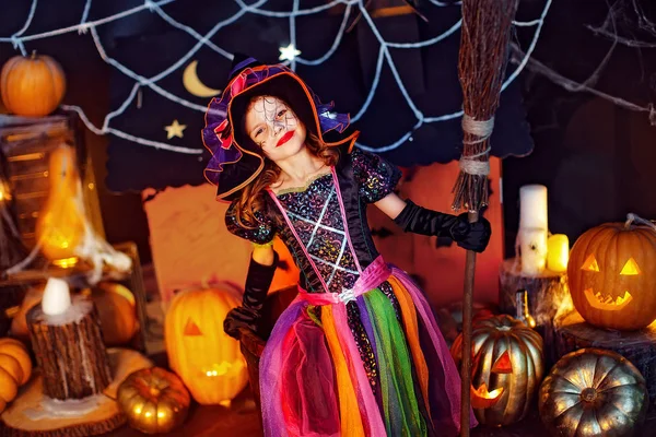 Retrato de una niña linda con un disfraz de bruja con escoba mágica . — Foto de Stock