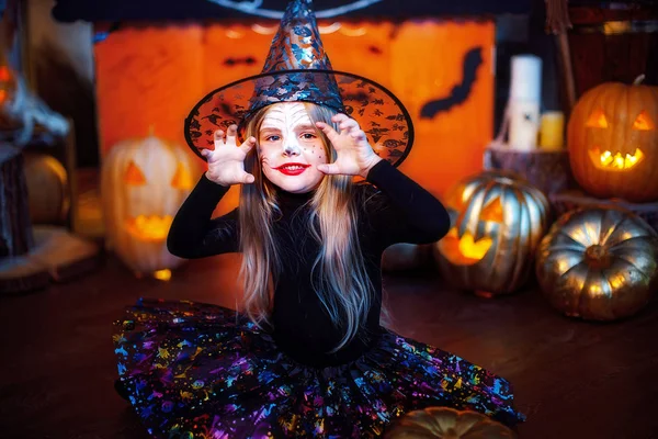 Feliz Halloween. Una niña hermosa en un disfraz de bruja celebra con calabazas — Foto de Stock