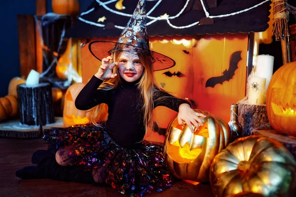 Feliz Dia das Bruxas. Uma menina bonita em um traje de bruxa celebra com abóboras — Fotografia de Stock