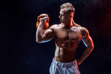 Kettlebell ile egzersiz yapan konsantre kaslı adam.