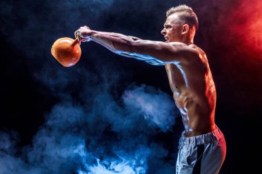 Kettlebell ile egzersiz yapan konsantre kaslı adam.