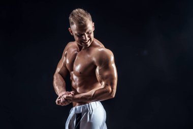 Stüdyoda poz veren yakışıklı güçlü vücut geliştirici.