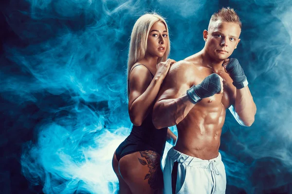 Aantrekkelijke paar, een slanke blonde vrouwelijke en knappe shirtless vent poseren in studio op een donkere gestructureerde achtergrond. — Stockfoto