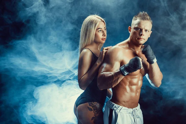 Atractiva pareja, una delgada rubia y guapo chico sin camisa posando en el estudio sobre un fondo de textura oscura . — Foto de Stock