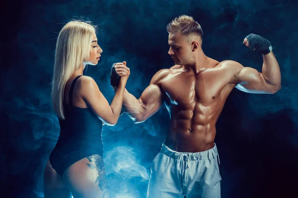 Atraktivní pár, štíhlá blondýna ženské a pohledný shirtless chlap pózuje ve studiu na tmavý podklad s texturou. — Stock fotografie