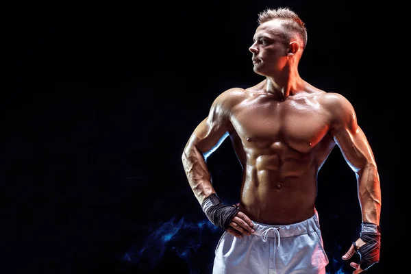 Guapo fuerte culturista posando en estudio sobre humo fondo — Foto de Stock