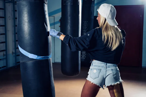 Mulher concentrada fazendo um treino de boxe fitness com um saco de perfuração . — Fotografia de Stock