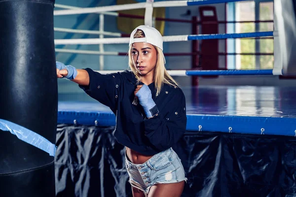 Mujer concentrada haciendo un entrenamiento de boxeo fitness con un saco de boxeo . — Foto de Stock