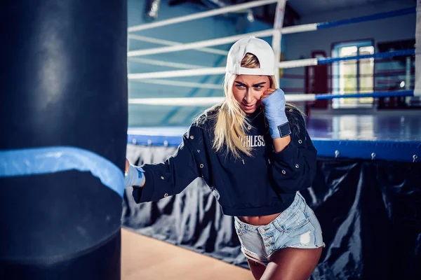 Mujer concentrada haciendo un entrenamiento de boxeo fitness con un saco de boxeo . — Foto de Stock