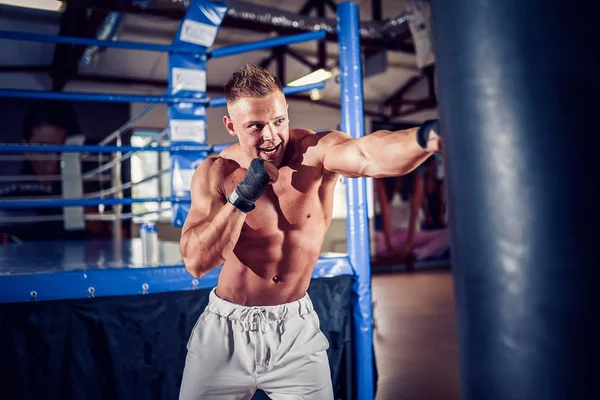 Manlig boxerträning med boxningssäck i mörk sporthall. — Stockfoto