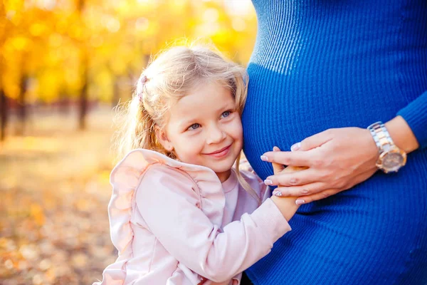 Güzel küçük kız hamile anneler karnında tutarak portresi — Stok fotoğraf