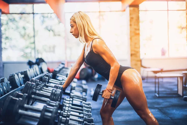 Γυναίκα μαυρισμένο αθλητικής καταλληλότητας κάνει ασκήσεις για την πλάτη και θέτοντας στο γυμναστήριο — Φωτογραφία Αρχείου