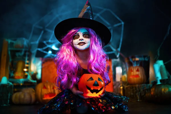Fröhliches Halloween. ein kleines schönes Mädchen im Hexenkostüm feiert mit Kürbissen — Stockfoto