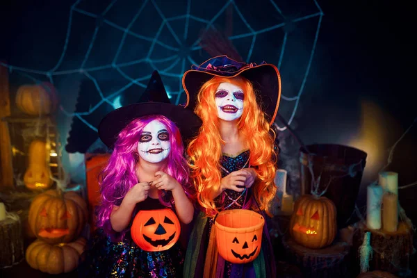 Duas irmãs engraçadas e fofas celebram o feriado. Crianças alegres em trajes de carnaval prontos para o Halloween . — Fotografia de Stock