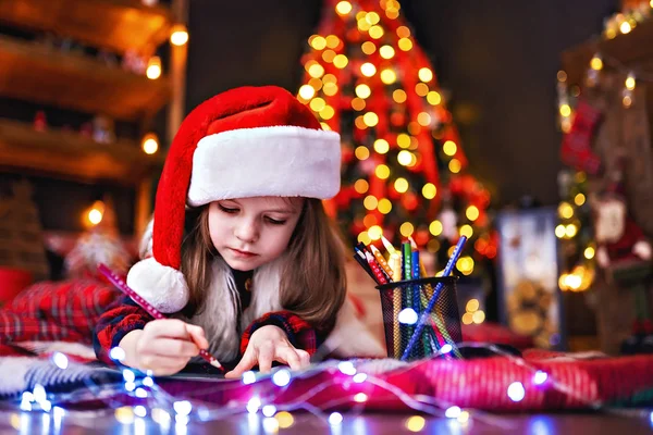 Zabawna dziewczyna w santa hat pisze list do santa — Zdjęcie stockowe