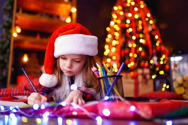 Zabawna dziewczyna w santa hat pisze list do santa — Zdjęcie stockowe
