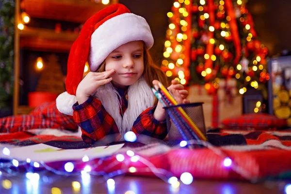 Zabawna dziewczyna w santa hat pisze list do santa — Zdjęcie stockowe