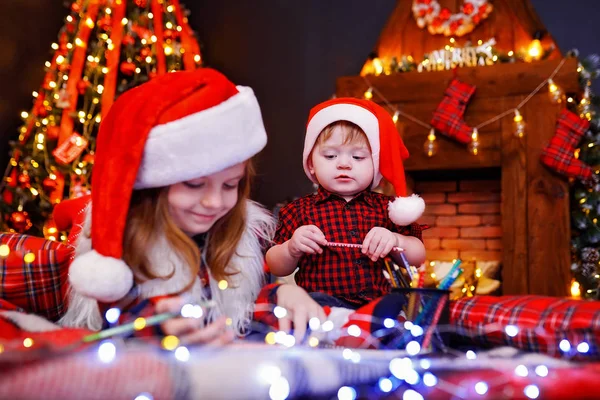 Rolig tjej i Santa hatt skriver brev till Santa och brodern liitle — Stockfoto