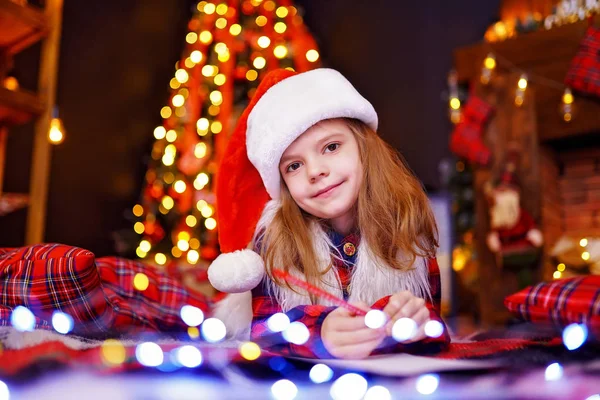 Rolig tjej i santa hatt skriver brev till santa — Stockfoto